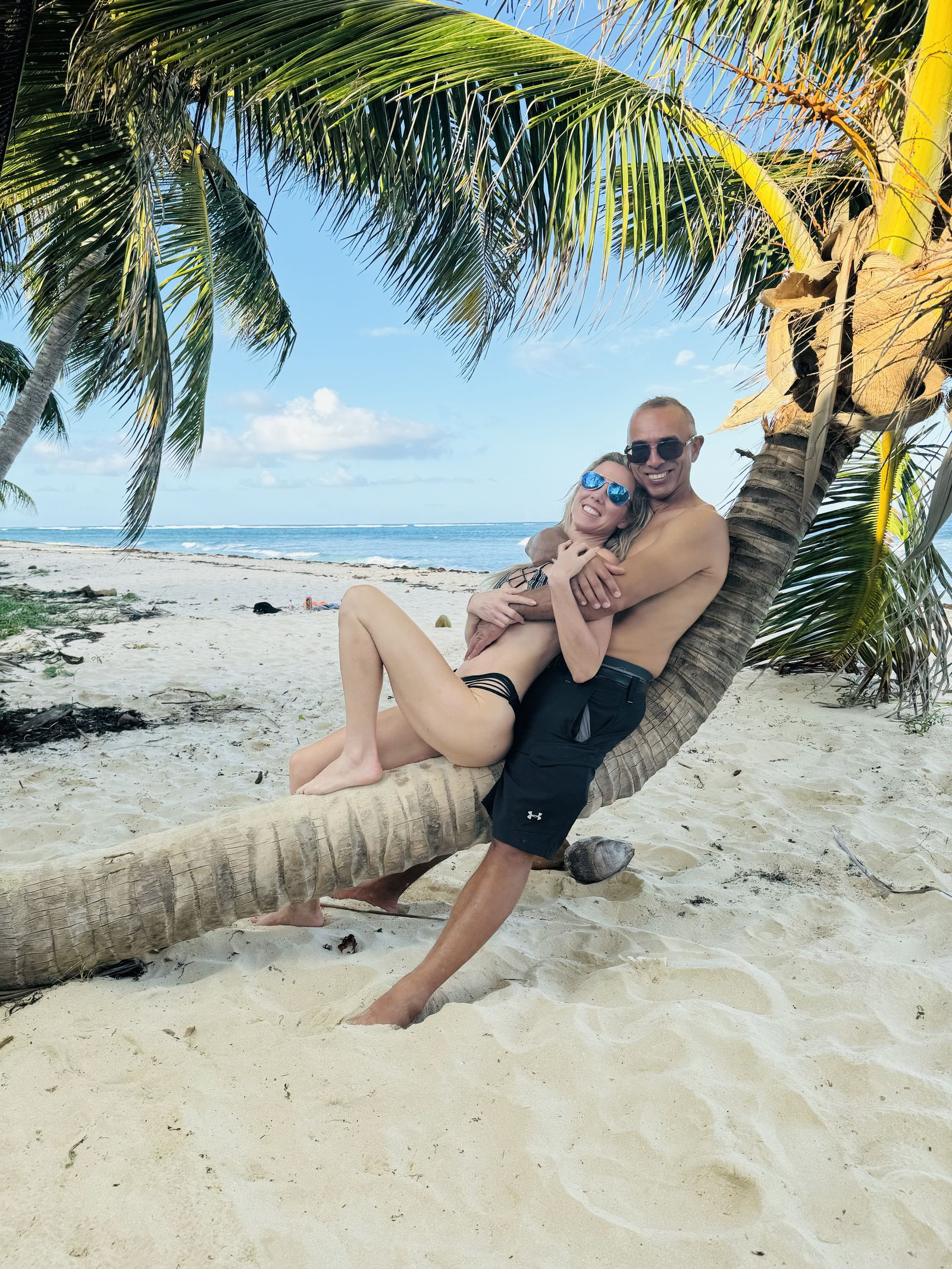 Guests embrace on a palm-fringed tropical beach