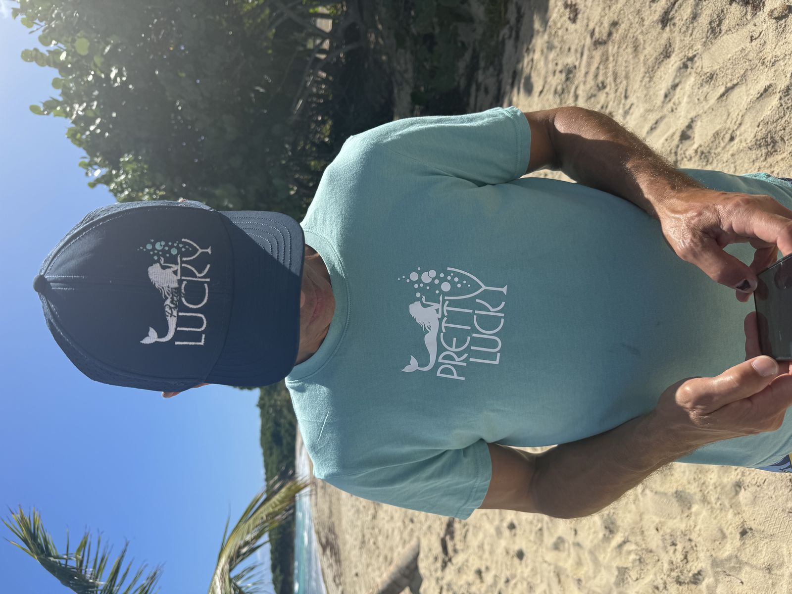 Guest in a Pretty Lucky tee on the beach