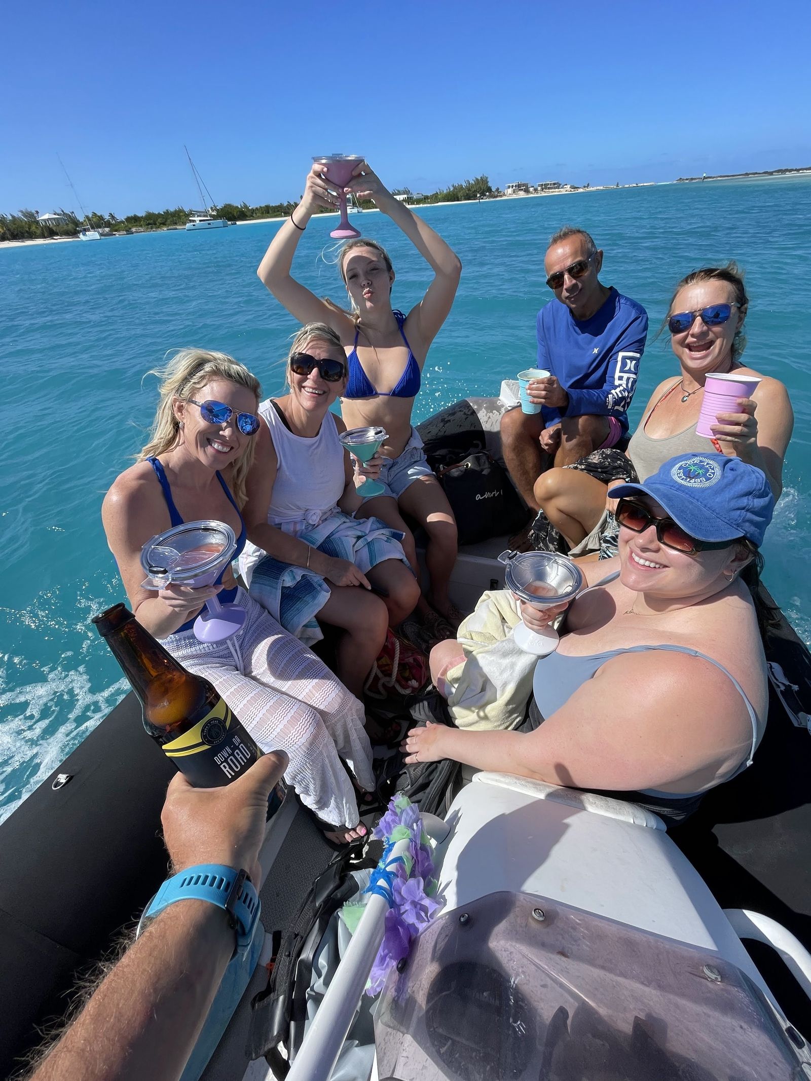 Guests toasting aboard a small boat in turquoise water